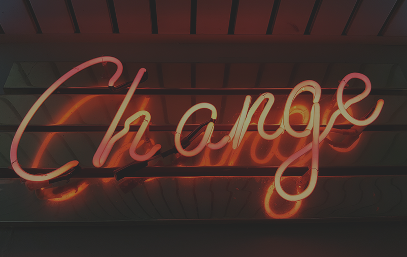 an orange neon sign spelling out “change” in cursive script