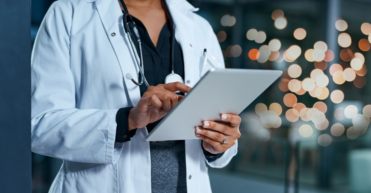 Healthcare professional using a digital tablet in a modern facility, symbolizing interconnected care and the integration of technology in smart hospital ecosystems.