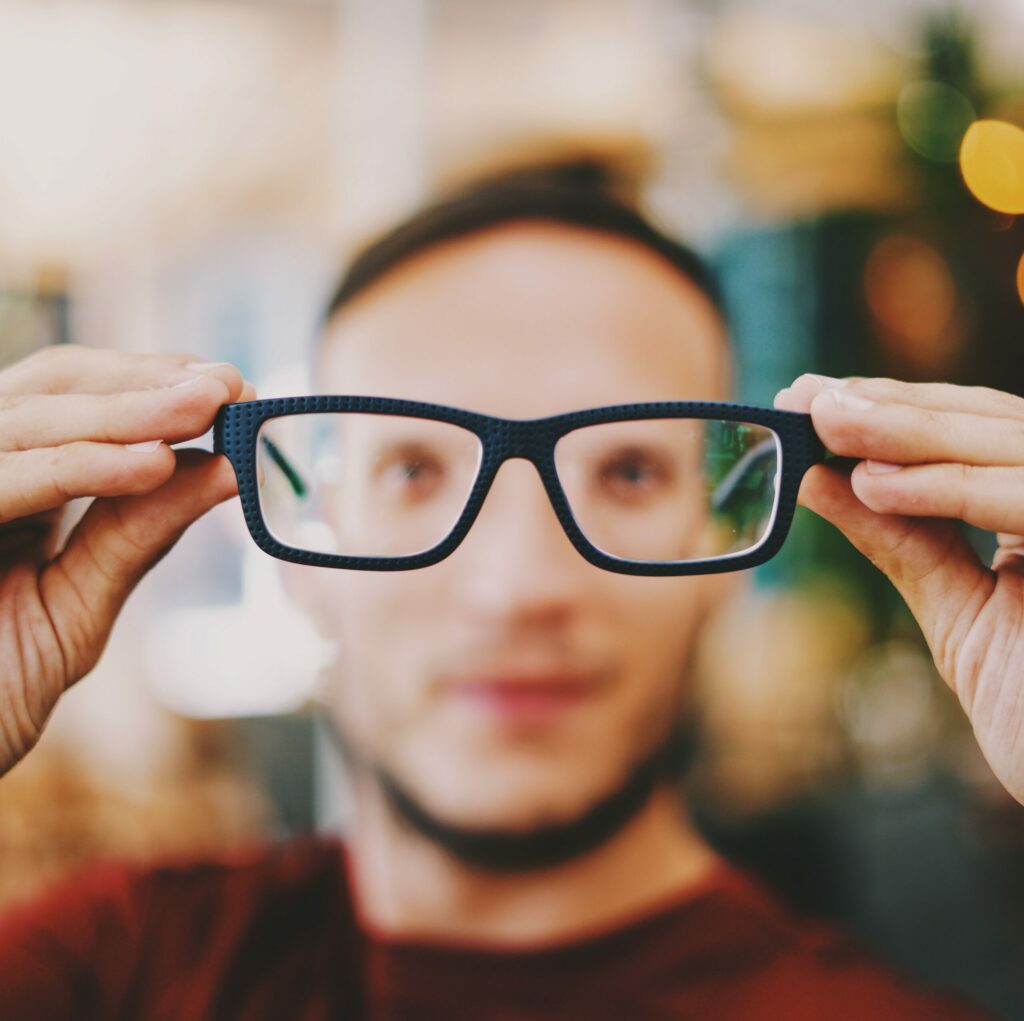 Man holding glasses away from his face